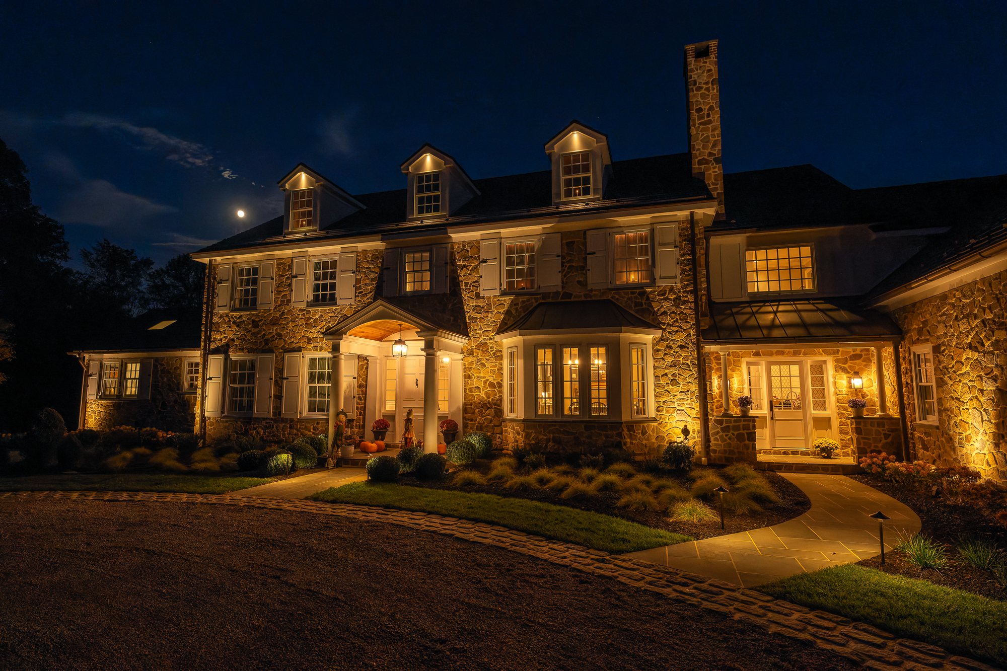 LED landscape lighting Main Line PA — warm LED uplighting on a stone home
