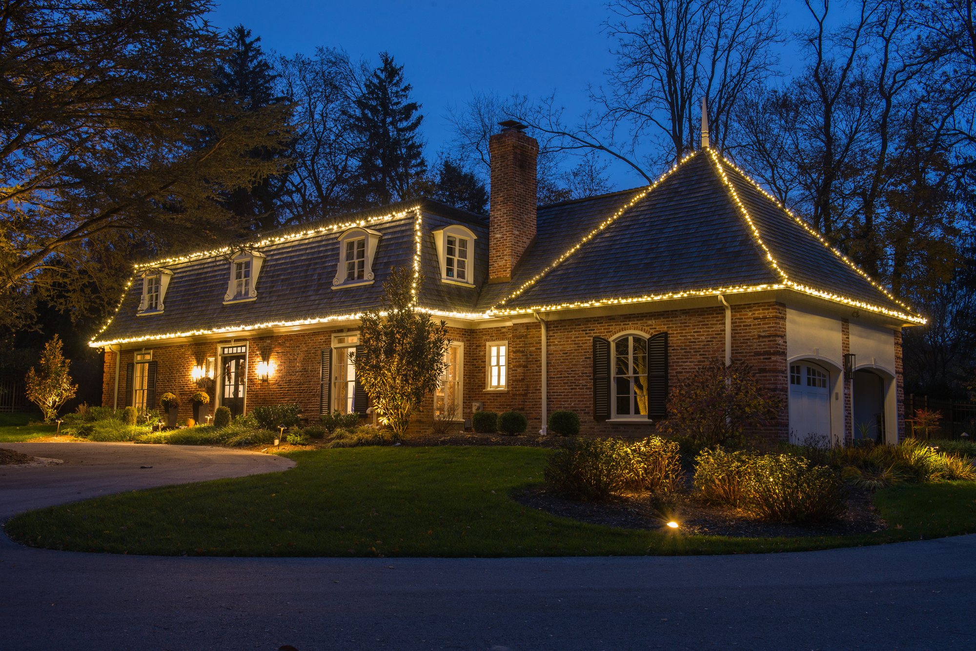 Holiday and Christmas lighting Main Line PA — warm white roofline holiday lighting on a brick home